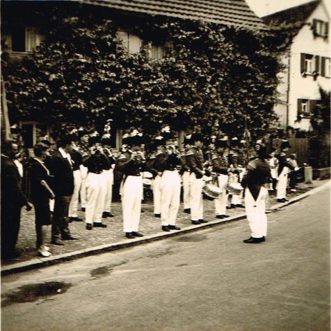 Der am 06. Juni 1952 gegründete langenburger Spielmanns- und Fanfarenzug beim Heimattag 1957. Gut zu erkennen an den schwarzen Zweispitz- Hüten mit den rot-weißen Federbüschen, roten Jacken und die weißen Hosen mit schwarz-goldenen Tressen. Rot-Weiß stand für das Haus Hohenlohe, Schwarz-Gold für die Stadt Langenburg.