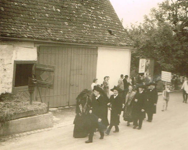 Trachtengruppe beim Heimattag 1957 vor dem Haus Bliesener. Das Haus mit Scheune und Miste zur Dorfstrasse stand zwischen dem Rathaus / Schulhaus und der heutigen Metzgerei Fritz.