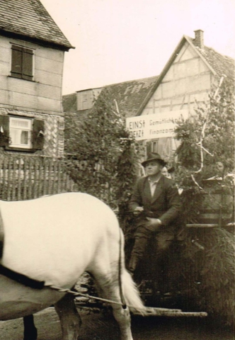 Vermutlich der „Bückeles-Bauer“ Herrmann Düring beim Umzug des Heimattag 1957. Sein Wagen mit der Aufschrift „EINST Gemütlichkeit – JETZT Finanzamt“ wird von Pferden gezogen.